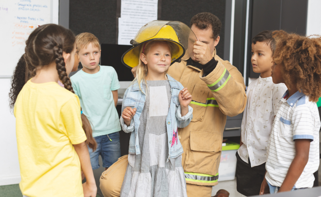 A fireman is helping WITS as a community leader and speaking with students. He is putting his hand on a child to share what its like to be a firefighter