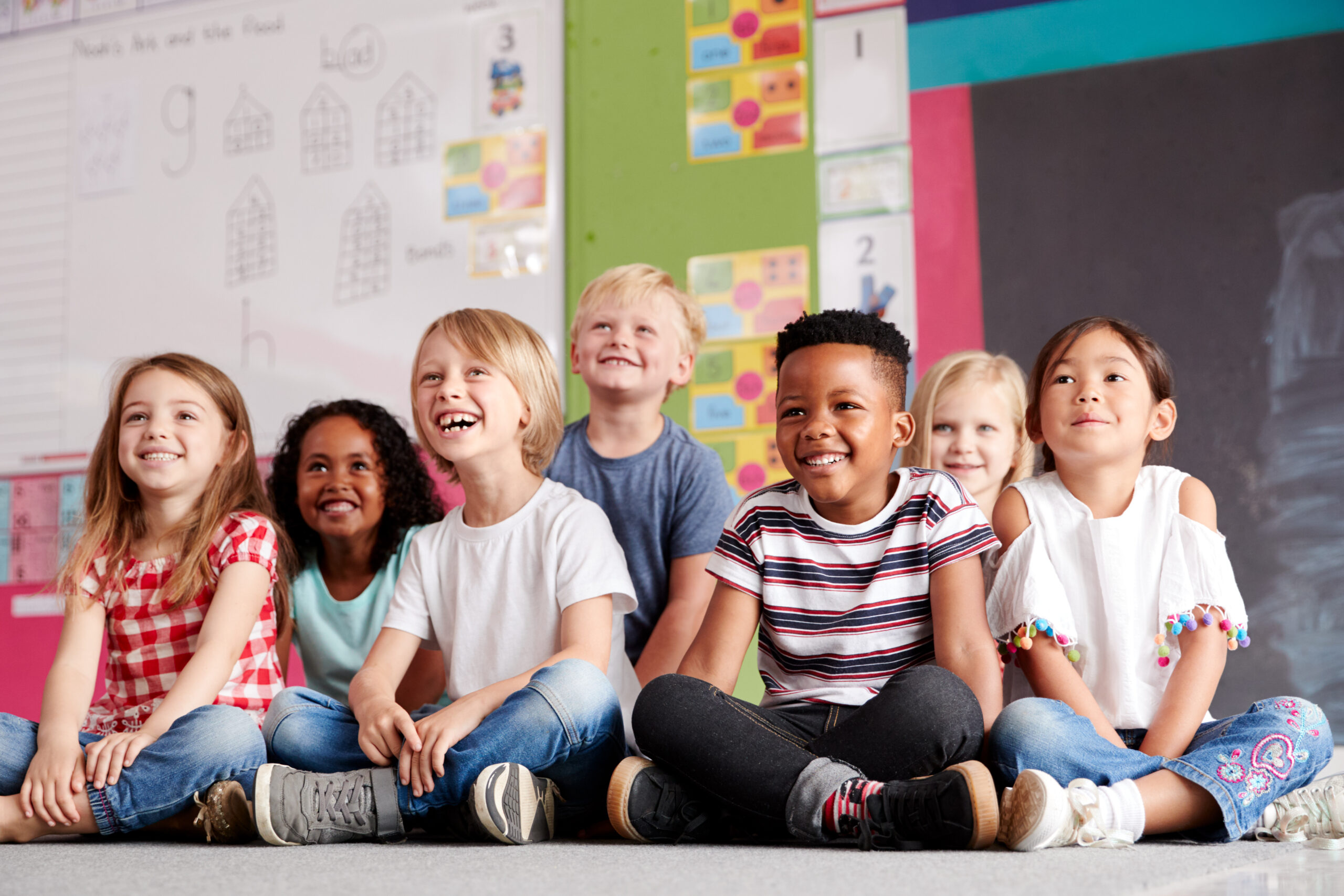 Groupe d'élèves d'école primaire assis par terre dans une salle de classe